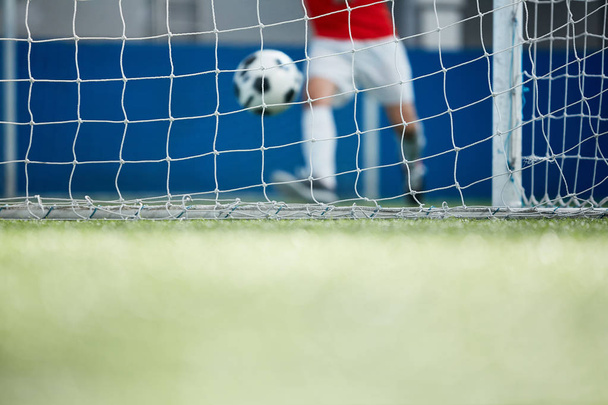 サッカー ネットと実行中のサッカー選手のゲートに向かって移動しながらボールを追求 - 写真・画像