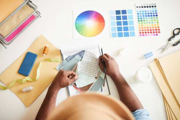 Přehled módních návrhářů na stole s tkaninové ukázky, vzorníky barev a jinými zásobami během pracovního procesu - Fotografie, Obrázek