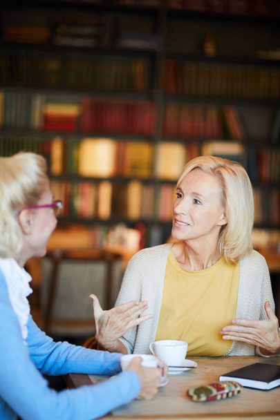 Femme blonde confiante expliquant ce qu'elle pense du sujet de sa conversation avec un ami par tasse de thé
 - Photo, image