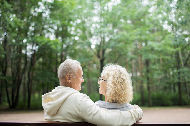 Widok z tyłu wieku małżonków patrząc na siebie podczas rozmów podczas posiedzenia w parku - Zdjęcie, obraz