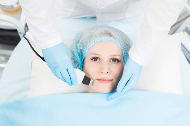 Kosmetyczka współczesnej kliniki lub salon Spa podejmowania miękkie procedury kosmetyczne na twarz klienta z urządzenia elektrycznego - Zdjęcie, obraz