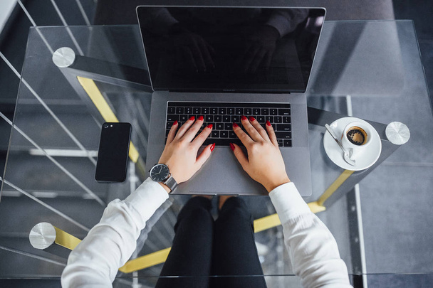 siyah pahalı saat, cam masa laptop, smartphone ve kahve ile ellerinde kadınla - Fotoğraf, Görsel