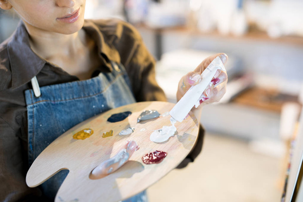 Jeune peintre mettant des peintures acryliques sur la palette en bois avant le processus de travail
 - Photo, image