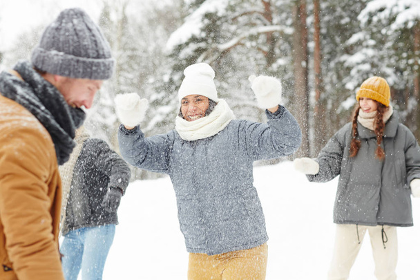 Pozitív fiatalok játszanak a hóban téli séta: vidám vegyes verseny lány, fehér ujjatlan élvezi hógolyó harcot a barátokkal - Fotó, kép