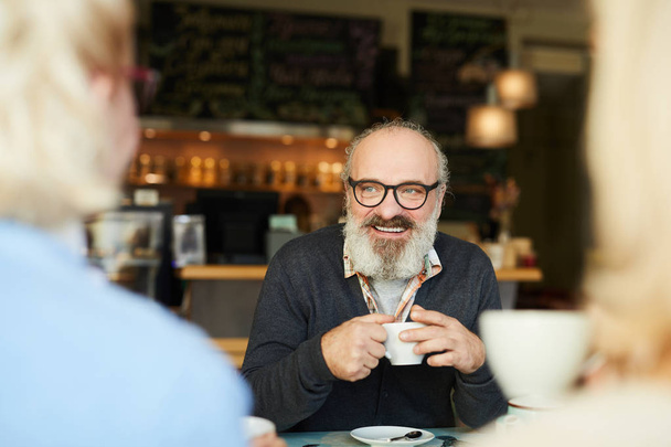 Χαμογελώντας ανώτερος άνθρωπος με φλυτζάνι του τσαγιού περνούν χρόνο με τους φίλους του από το φλιτζάνι του τσαγιού στο καφέ - Φωτογραφία, εικόνα