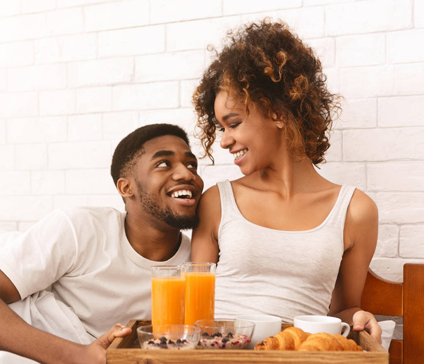 Heureux couple noir profiter du petit déjeuner au lit
 - Photo, image