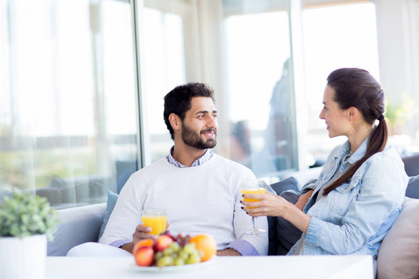 Young couple in casualwear relaxing in hotel cafe, drinking juice and having pleasant talk - Фото, изображение