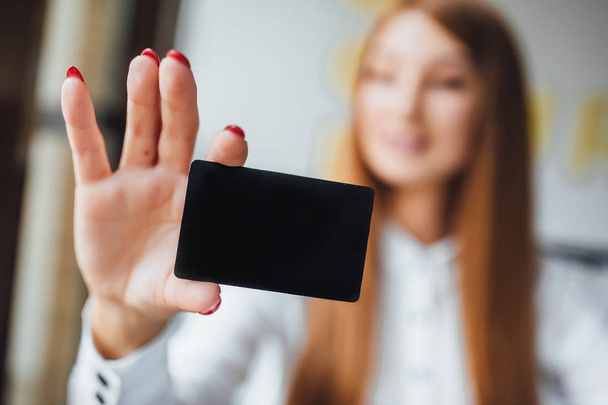 Businesswoman with red nails holding black credit card in one hand, selective focus - Foto, immagini