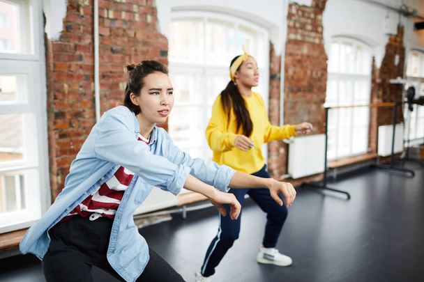 Genç aktif kadın ve grup arkadaşı modern stüdyoda hip hop dansı öğreniyorlar. - Fotoğraf, Görsel