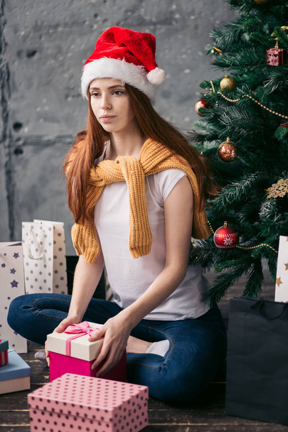 sad unhappy girl sitting in front of the Cristmas tree - 写真・画像