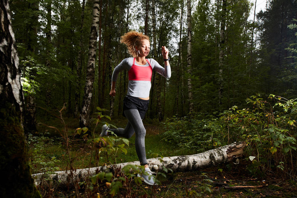 Mladá aktivní sportovkyně běžící v břízovém lese o letním víkendu nebo ráno - Fotografie, Obrázek