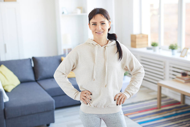 Young sporty woman in activewear looking at you while exercising at home - Photo, image