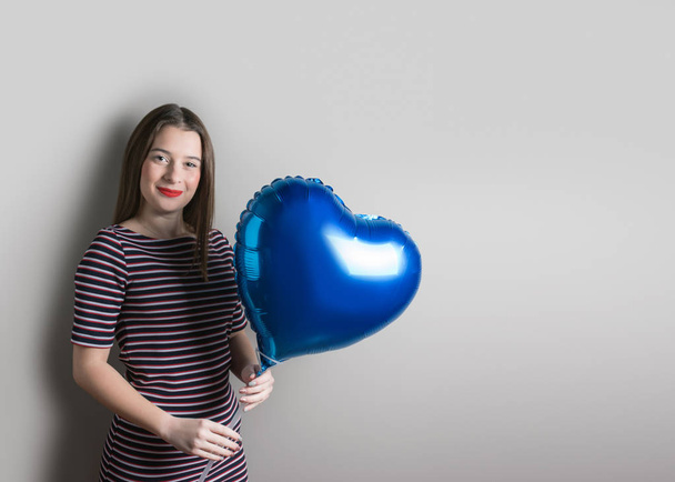 Beautiful young girl with heart shape balloon on bright  backgro - Photo, Image
