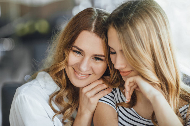 Mom and young daughter hugging on summer terrace in casual clothing, selective focus - Фото, зображення