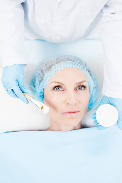 Mujer de mediana edad acostada en la almohada y con procedimiento cosmético en la piel de la cara
 - Foto, imagen