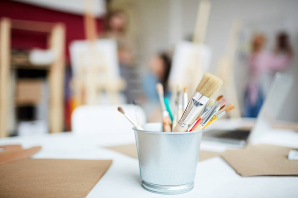 Piccolo secchio con mazzo di pennelli e carte su posto di lavoro di artista in studio
 - Foto, immagini