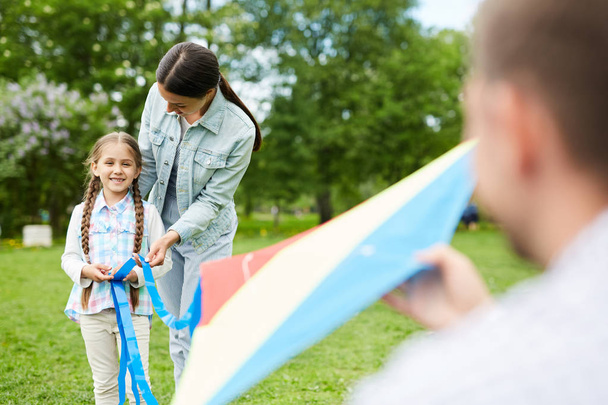 entzückendes kleines Mädchen und ihre jungen Eltern beim Freizeitspielen mit dem Drachen im Park - Foto, Bild