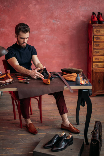 young attractive cobbler measuring the leather for shoe - Fotó, kép