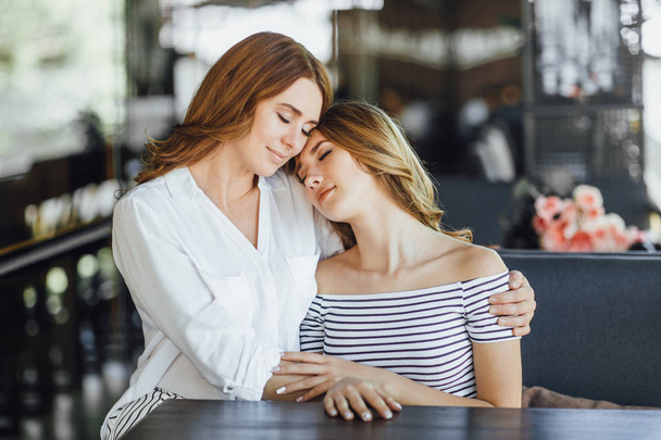 Mom and young daughter hugging on summer terrace in casual clothing, selective focus - Foto, Imagen