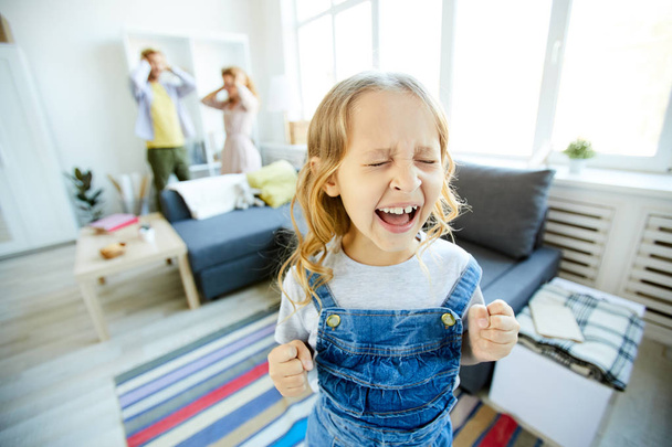 Youthful daughter crying and screaming loudly while being naughty with her shocked parents on background - Fotoğraf, Görsel