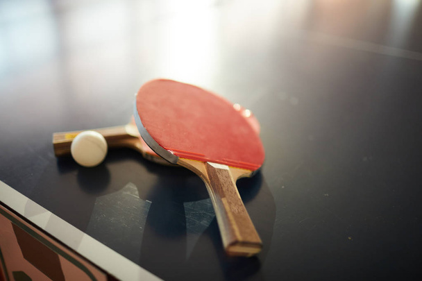 Настільні тенісні ракетки і м'яч для двох гравців пінг-понг в сучасному спортивному центрі або залі
 - Фото, зображення