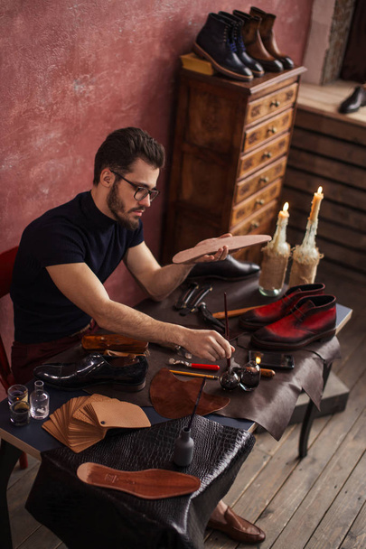 man in glasses applying color in the soles - Foto, Imagem