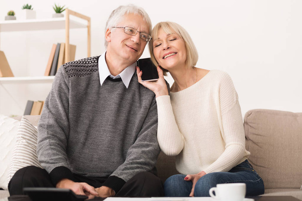 Senior couple sharing smartphone, having phone call - Photo, Image