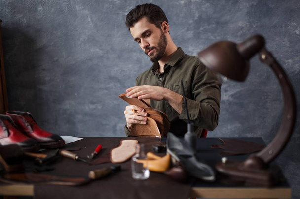 young awesome craftsman working with different kinds of leather - Valokuva, kuva