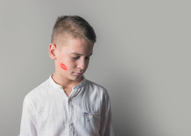 Cute boy with lipstick kiss on his face on bright background. - Foto, immagini