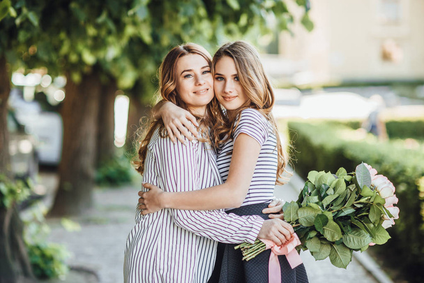 young blonde daughter hugging  mom on street of city - 写真・画像