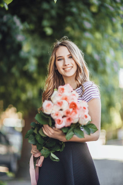 Portrait of beautiful young woman standing with bunch of roses  - Foto, Imagen