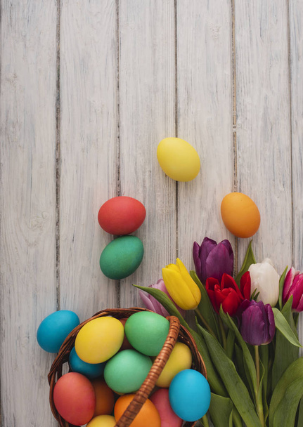 Colorful easter eggs,spring tulips  on wooden texture background.On a white wood table,colored eggs,colors flowers.Happy religious day,traditional for people. Top view.Copy space. - Fotó, kép