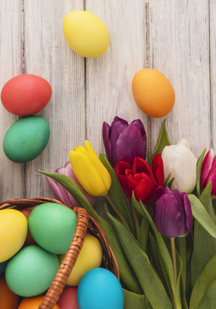 Colorful easter eggs,spring tulips  on wooden texture background.On a white wood table,colored eggs,colors flowers.Happy religious day,traditional for people. Top view.Copy space. - Foto, Bild