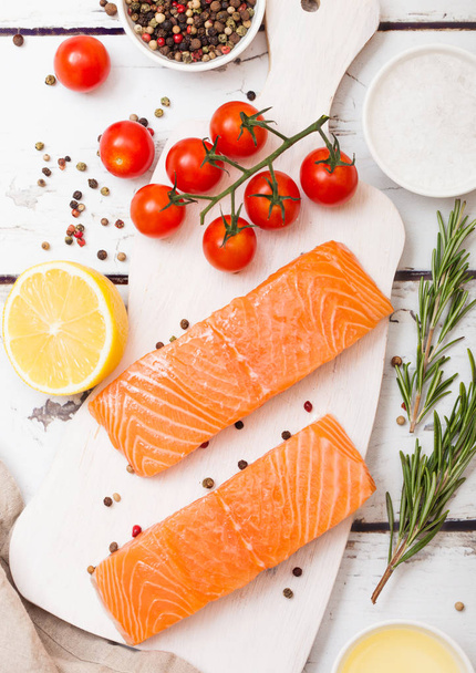 Plastic container with fresh salmon slice with oil tomatoes and lemon on wooden kitchen background.  - Foto, Imagen