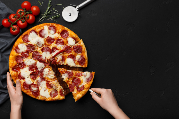 Vrouw nemen stuk van peperoni pizza met spatel - Foto, afbeelding