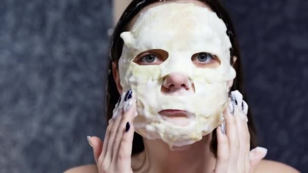 Mujer aplicando máscara de espuma cosmética en su cara y mirando a la cámara, concepto de cuidado de la piel
 - Metraje, vídeo