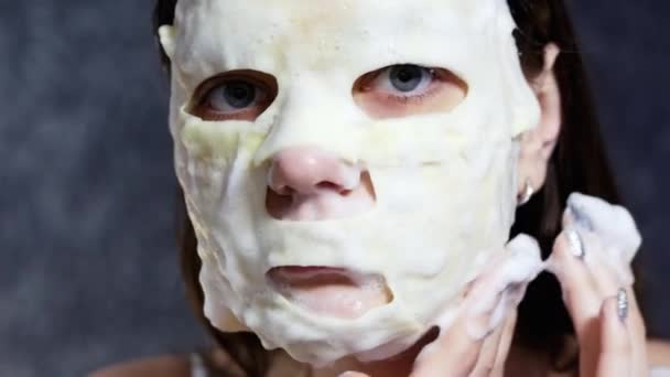 Žena použití pěnové maska na obličej a při pohledu na fotoaparát, kůže péče o koncept - Záběry, video