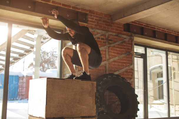 Caucasian Athletic man performing plyo box jump exercise during crossfit workout - Foto, Bild
