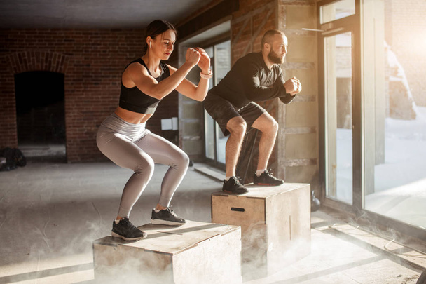 Man and woman jumping tohether on boxes in gym, funcrional workout for people - Foto, Imagem