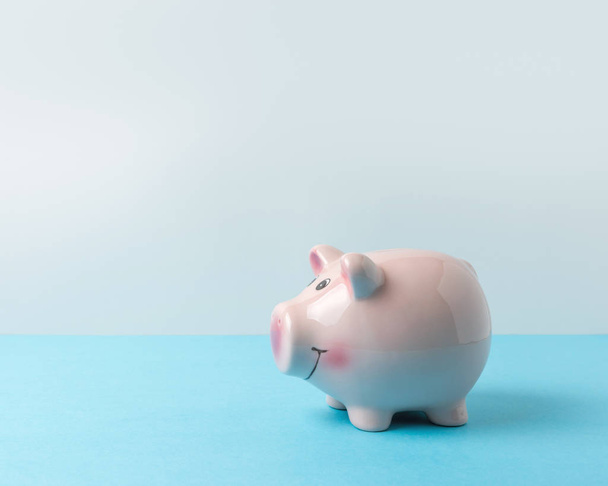 Piggy bank on blue table. Saving money concept. - Fotó, kép