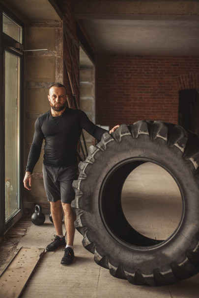 Young caucasian muscular man flipping heavy tire in gym - Fotografie, Obrázek