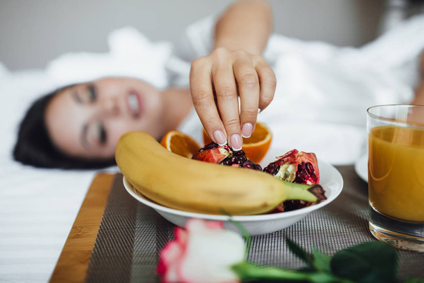 beautiful brunette woman in morning, next to croissant, orange juice and banana, selective focus - Foto, afbeelding