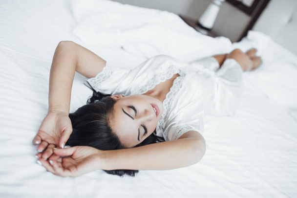 young beautiful brunette woman lying in bed in morning - Fotoğraf, Görsel