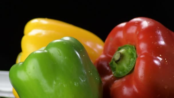 Pimentas amarelo, vermelho e verde legumes girando em fundo preto
 - Filmagem, Vídeo