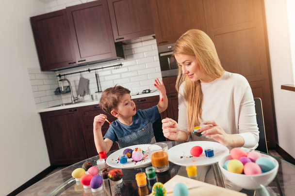 Portrait of happy young woman painting Easter eggs with her adorable little son - Φωτογραφία, εικόνα