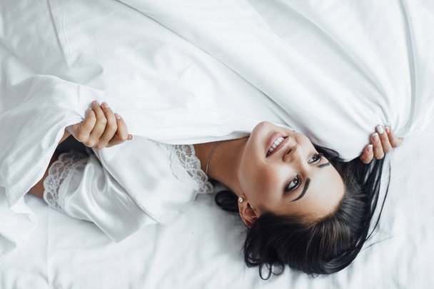 young brunette woman lying in bed waking up in morning and sweating - Photo, Image