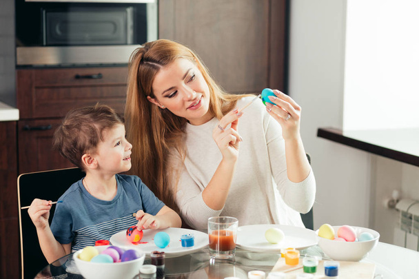 Feliz Pascua Joven madre y su pequeño hijo pintando huevos de Pascua. - Foto, Imagen