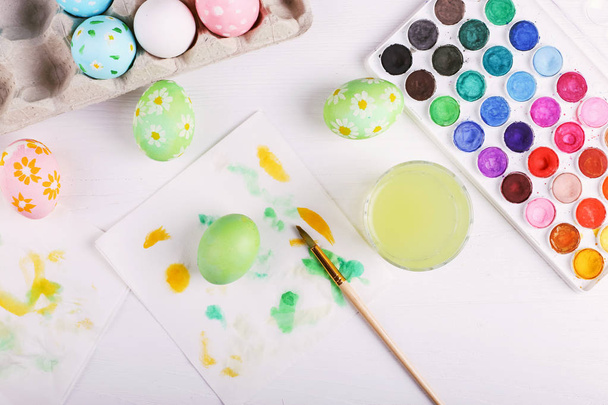 Hand painted Easter eggs, paints and brushes on a white table. Preparation for the holiday. - Фото, зображення