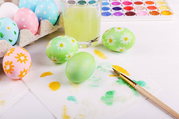 Hand painted Easter eggs, paints and brushes on a white table. Preparation for the holiday. - Fotografie, Obrázek