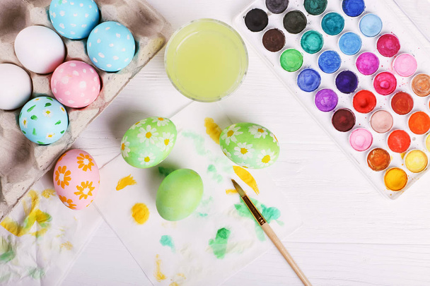 Hand painted Easter eggs, paints and brushes on a white table. Preparation for the holiday. - Photo, Image